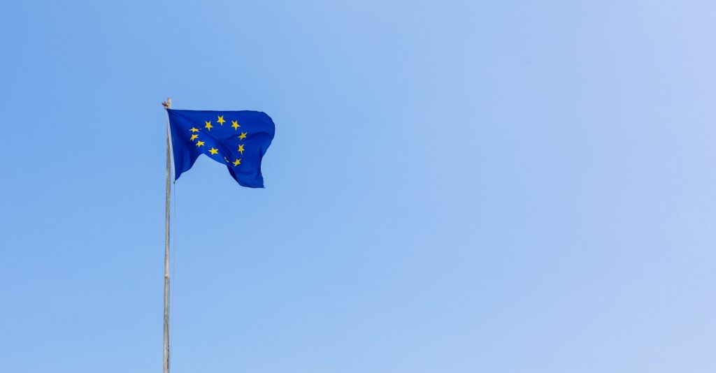 European Union EU flag is flying on blue sky background. Banner, place for text