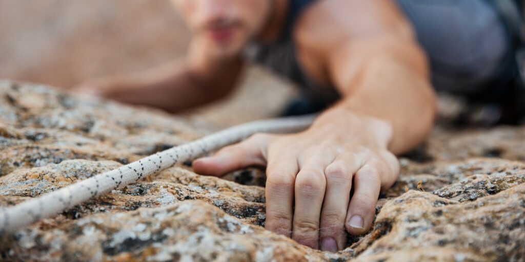 Man reaching for a grip while he rock climbs