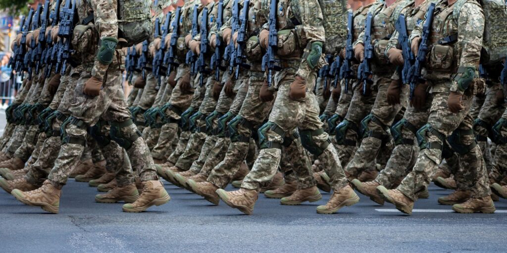 Military soldiers march in a parade with weapons. Pixel uniform. Soldier's legs. Military background