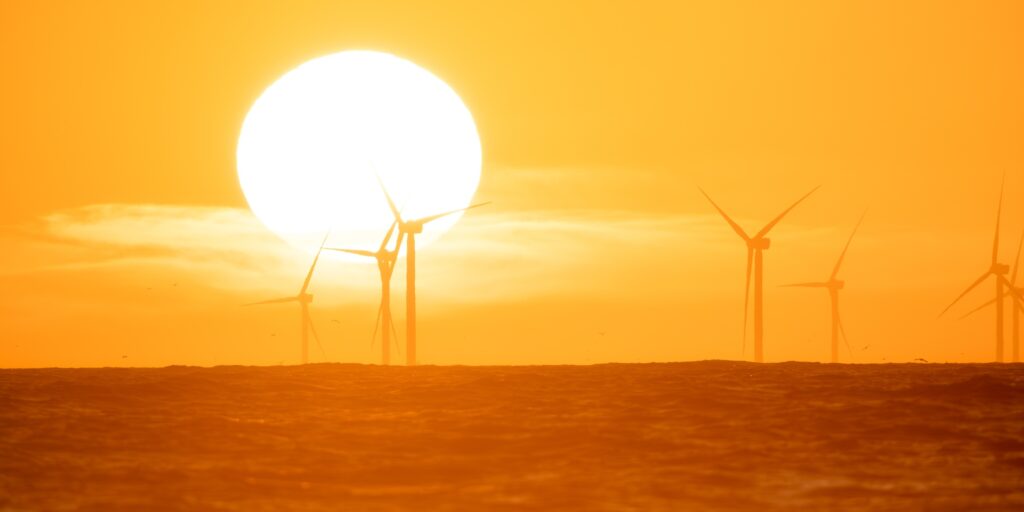 Wind turbine on the sea during sunset. Renewable energy sources.