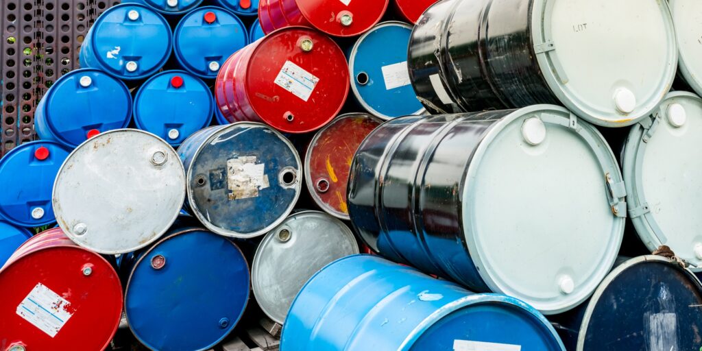 Old chemical barrels on wooden pallet. Blue and red oil drum. Steel and plastic oil tank. Toxic