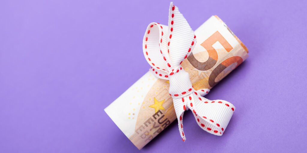 fifty euro banknote money roll tied with a white gift ribbon isolated on a purple background