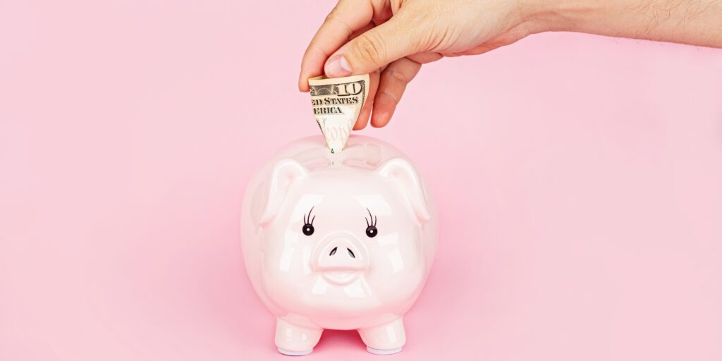 Piggy bank, cash and hand putting cash money