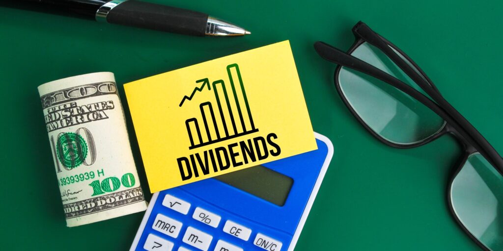 calculator, glasses, pen and paper money with the word dividend.