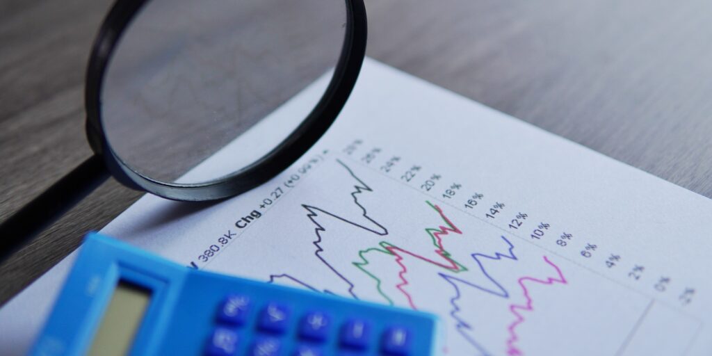 Closeup image of calculator, magnifying glass and line graph.