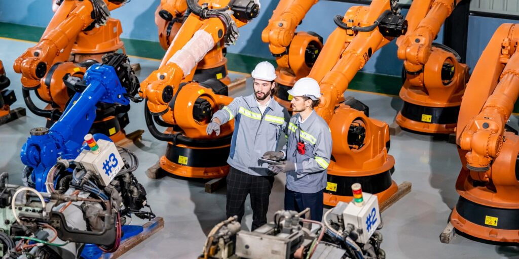 Engineer inspecting automatic AI robot arm and machines in factory. Engineer inspecting automatic AI