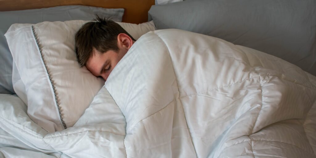Young man asleep in bed at home