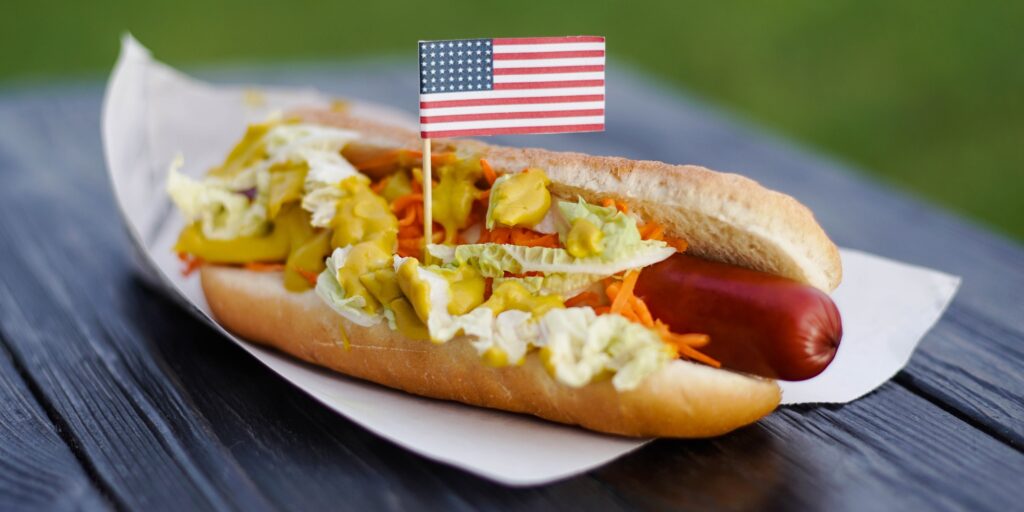 American patriotic hot dog on wooden board with USA flag. Celebrating Independence day on 4th July.