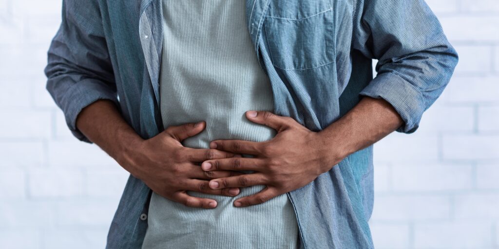 Black Guy Touching Aching Abdomen Having Stomachache, Gray Background, Cropped