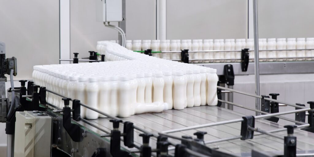 Factory producing milk or yogurt in to plastic bottles on conveyor line. Equipment at dairy plant
