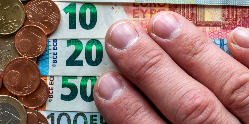 Hand fingers on background of neatly arranged stack of euro banknotes, currency bills worth ten