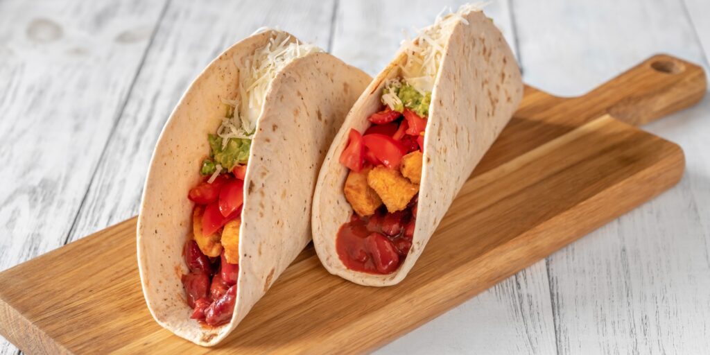 Taco with filling on the wooden background