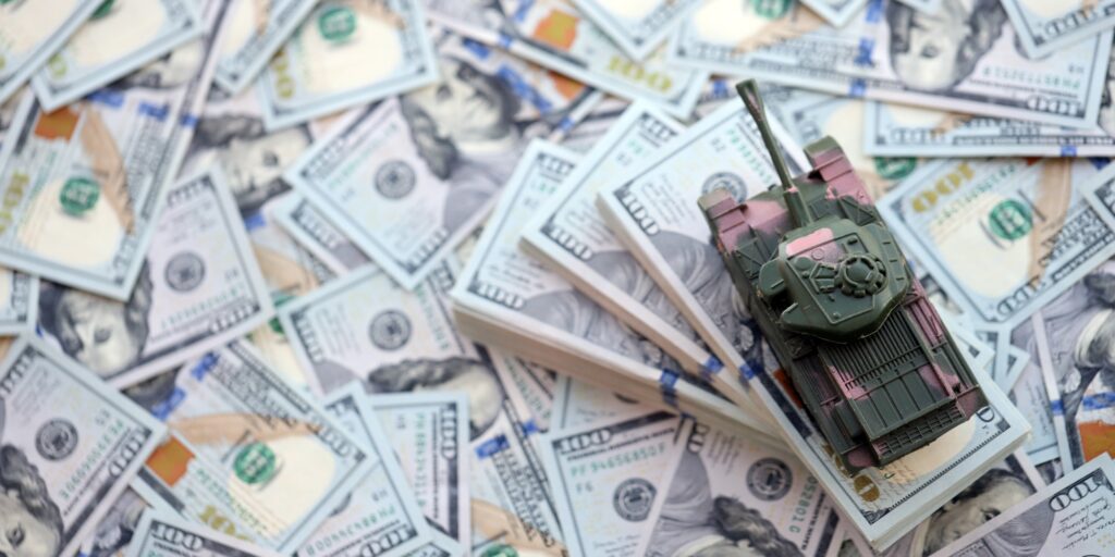 Toy tank on US hundred dollar bills banknotes. The concept of war costs