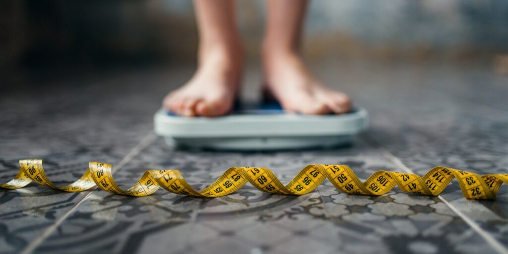 Female feet on the scales, measuring tape