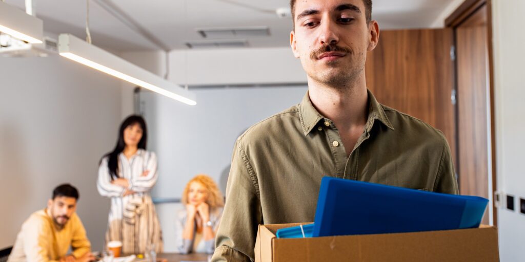 Portrait of businessman holding box of personal belongings being fired from work.